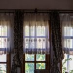Sunlit room with elegant traditional curtains overlooking a garden view.